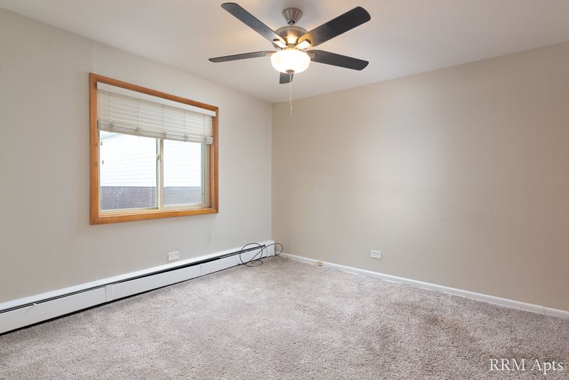 Carpeted bedroom with ceiling fan and window, Park Avenue apartment 204
